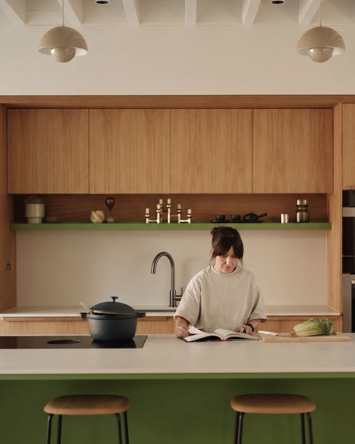 Cocina de madera con isla verde y mezcladora de caño curvo en acabado grafito