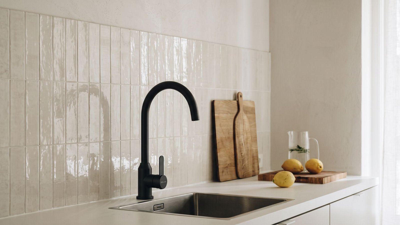Mezcladora de cocina de caño curvo en negro mate junto a fregadero